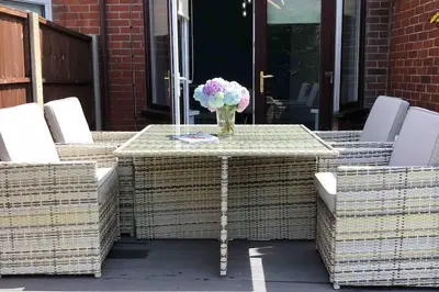 a table with wicker chairs and a vase of flowers at Spacious Family Home Minutes from the Beach in Blackpool