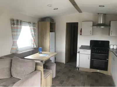 a living room with a couch and a table in a kitchen at A family-friendly, eight birth, 2019 Abbey Trieste Caravan in Morecambe