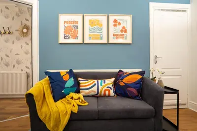a living room with a gray couch with colorful pillows at Stanley Park House - Air Host & Stay - Anfield in Liverpool