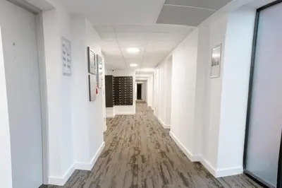 an empty hallway in an office building with white walls and wood floors at Contemporary 1 Bed Apartment in Central Liverpool in Liverpool
