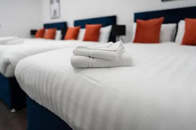 two beds with white towels sitting on top of them at New Zealand House Apartments by Happy Days in Liverpool