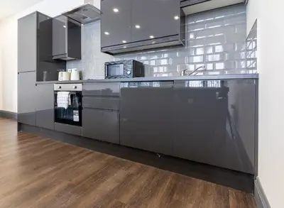 a kitchen with stainless steel appliances and wood floors at New Zealand House Apartments by Happy Days in Liverpool