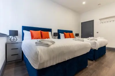 two beds in a bedroom with orange and blue at New Zealand House Apartments by Happy Days in Liverpool