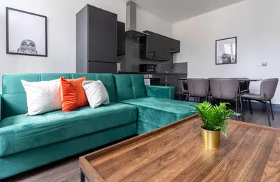 a living room with a green couch and a table at New Zealand House Apartments by Happy Days in Liverpool