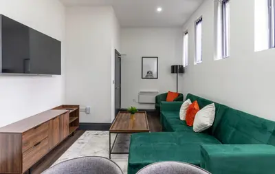 a living room with a green couch and a table at New Zealand House Apartments by Happy Days in Liverpool