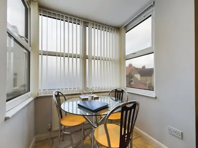 a dining room with a table and chairs and windows at The Beach House, Luxury Apartments in Blackpool