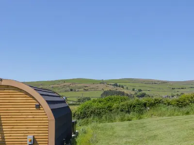 a large wooden building on a hill with a field at Holly in Ulverston
