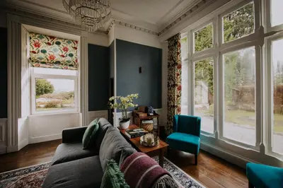 a living room with a couch and windows at The Pheasant Lodge Spacious Georgian Apartment with Log Fire and Garden Views in Grange Over Sands
