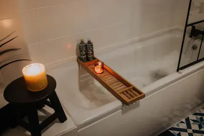 a bathroom with a bath tub with a candle and a table at The Pheasant Lodge Spacious Georgian Apartment with Log Fire and Garden Views in Grange Over Sands