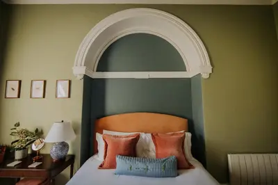 a bedroom with an arch above a bed with orange pillows at The Pheasant Lodge Spacious Georgian Apartment with Log Fire and Garden Views in Grange Over Sands