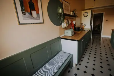 a kitchen with a bench in front of a counter at The Pheasant Lodge Spacious Georgian Apartment with Log Fire and Garden Views in Grange Over Sands
