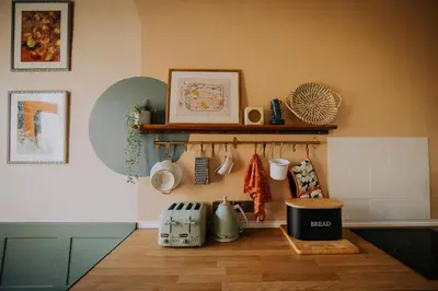 a kitchen counter with utensils and a shelf on the wall at The Pheasant Lodge Spacious Georgian Apartment with Log Fire and Garden Views in Grange Over Sands