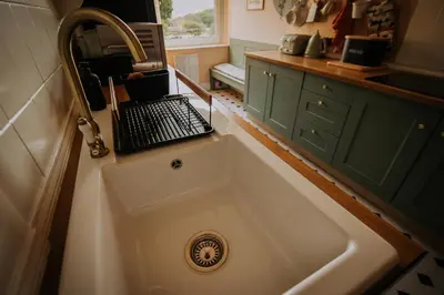 a kitchen sink with a laptop sitting on top of it at The Pheasant Lodge Spacious Georgian Apartment with Log Fire and Garden Views in Grange Over Sands
