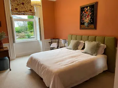 a bedroom with a large bed and a window at The Pheasant Lodge Spacious Georgian Apartment with Log Fire and Garden Views in Grange Over Sands
