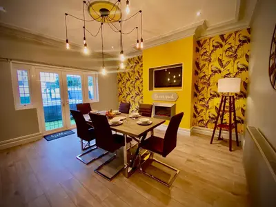 a dining room with a table and chairs and a yellow wall at Captivating 4-Bed Hot Tub House in Blackpool in Blackpool