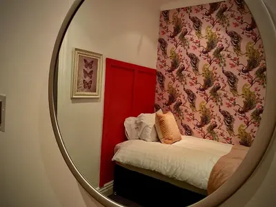 a mirror reflecting a bedroom with a bed with a red wall at Captivating 4-Bed Hot Tub House in Blackpool in Blackpool