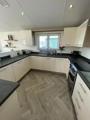 a kitchen with white cabinets and a wooden floor at LA07 Oceanview in Morecambe