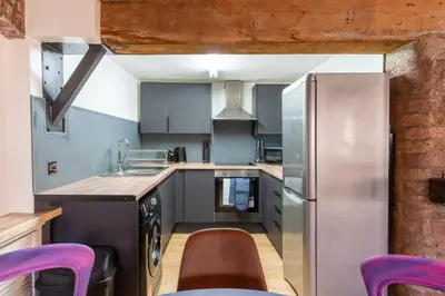 a kitchen with a stainless steel refrigerator and purple chairs at Rainford Gardens by UStay Aparthotels in Liverpool