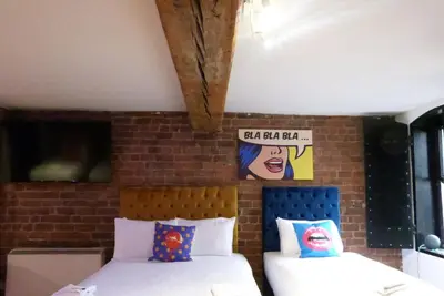 a bedroom with two beds and a brick wall at Rainford Gardens by UStay Aparthotels in Liverpool