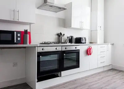 a kitchen with white cabinets and a black oven at Modern 5 Bed Near LFC Stadium in Liverpool