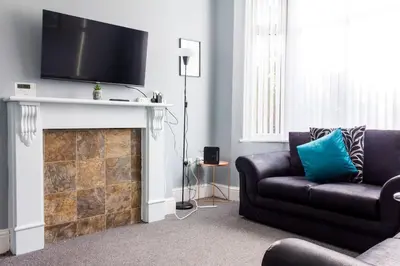 a living room with a couch and a tv over a fireplace at Modern 5 Bed Near LFC Stadium in Liverpool