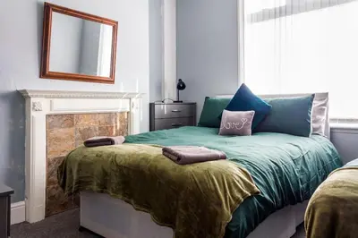 a bedroom with a green bed with a mirror at Modern 5 Bed Near LFC Stadium in Liverpool