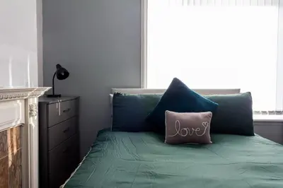 a green bed with a love pillow on it at Modern 5 Bed Near LFC Stadium in Liverpool