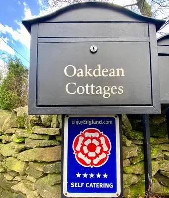a sign for a caledonian cottages on a stone wall at Ribble Cottage in The Ribble Valley in Whalley