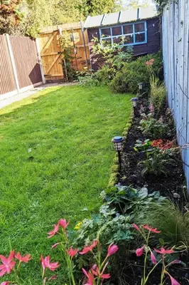 a backyard with a garden with pink flowers and a fence at 'Mill Cottage' Parbold in Parbold