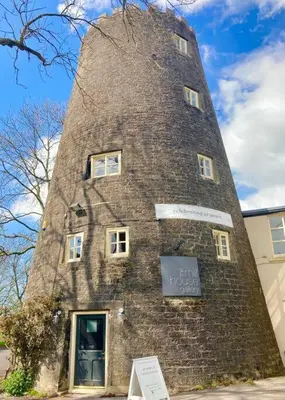 a tall brick tower with a sign in front of it at 'Mill Cottage' Parbold in Parbold