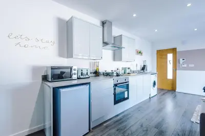 a kitchen with white appliances and a wooden floor at Formby Village Apartments By Greenstay Serviced Accommodation - Perfect For SHORT & LONG STAYS - Couples, Friends, Families & Business Travellers All Welcome - Dog Friendly - 7 in Formby