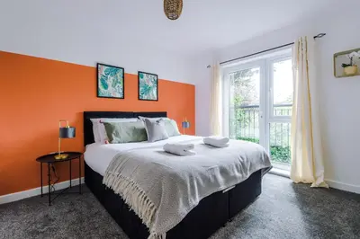 a bedroom with a large bed with an orange wall at Formby Village Apartments By Greenstay Serviced Accommodation - A Luxury 2 Bed Apt - Perfect for Couples, Friends, Families & Business Travellers - FREE Parking - Dog Friendly - Fast Wi-Fi - 6 in Formby