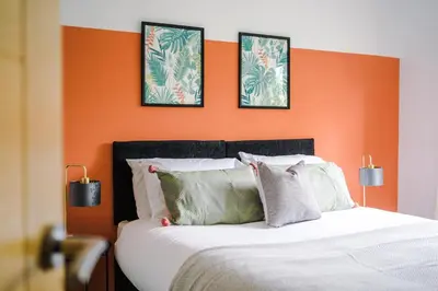 a bedroom with an orange accent wall with a bed at Formby Village Apartments By Greenstay Serviced Accommodation - A Luxury 2 Bed Apt - Perfect for Couples, Friends, Families & Business Travellers - FREE Parking - Dog Friendly - Fast Wi-Fi - 6 in Formby