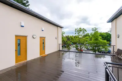 a balcony with a wooden floor and two doors at Formby Village Apartments By Greenstay Serviced Accommodation - A Luxury 2 Bed Apt - Perfect for Couples, Friends, Families & Business Travellers - FREE Parking - Dog Friendly - Fast Wi-Fi - 6 in Formby