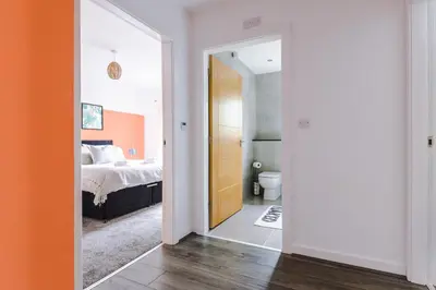 a bedroom with a bed and a door leading to a bathroom at Formby Village Apartments By Greenstay Serviced Accommodation - A Luxury 2 Bed Apt - Perfect for Couples, Friends, Families & Business Travellers - FREE Parking - Dog Friendly - Fast Wi-Fi - 6 in Formby