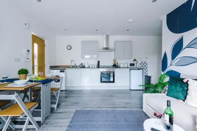 a living room and kitchen with a couch and a table at Formby Village Apartments By Greenstay Serviced Accommodation - A Luxury 2 Bed Apt - Perfect for Couples, Friends, Families & Business Travellers - FREE Parking - Dog Friendly - Fast Wi-Fi - 6 in Formby