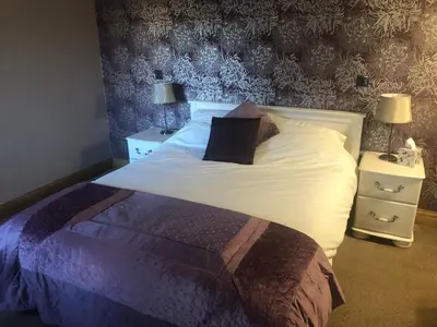 a bedroom with a bed and two night stands with two lamps at Heron House in Haverigg