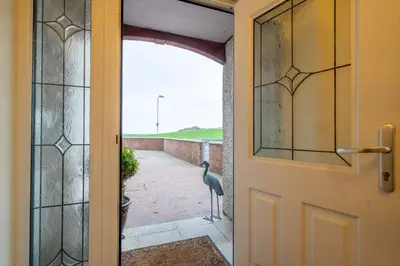 a bird standing on a patio outside a door at Heron House in Haverigg