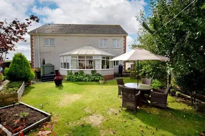 a house with a yard with a table and an umbrella at Heron House in Haverigg