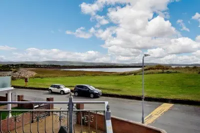 two cars parked in a parking lot next to a field at Heron House in Haverigg