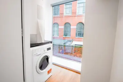 a laundry room with a washing machine and a window at Brand New Stunning City Centre Open Plan 1Bed in Liverpool
