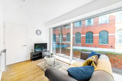 a living room with a couch and a large window at Brand New Stunning City Centre Open Plan 1Bed in Liverpool