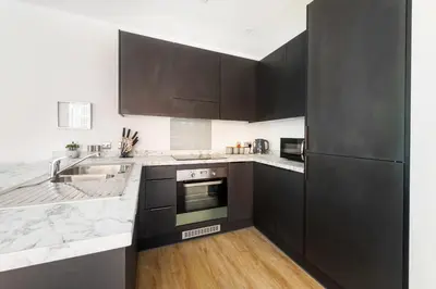 a kitchen with black cabinets and a sink at Brand New Stunning City Centre Open Plan 1Bed in Liverpool