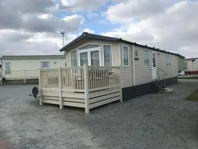 a small house with a wooden fence in a parking lot at Bobby's Bolthole in Heysham