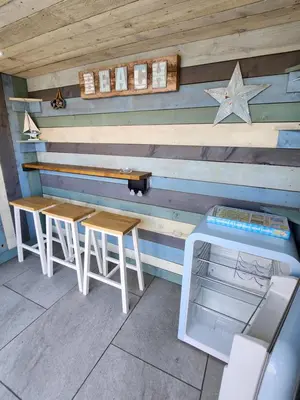 a wooden wall with two tables and a bench at Delightful newly renovated 3-bed house with garden beach hut in Blackpool