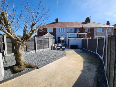a backyard of a house with a fence and a tree at Delightful newly renovated 3-bed house with garden beach hut in Blackpool