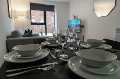 a table with plates and wine glasses on it at Contemporary 1 Bed Apartment in Liverpool Centre in Liverpool