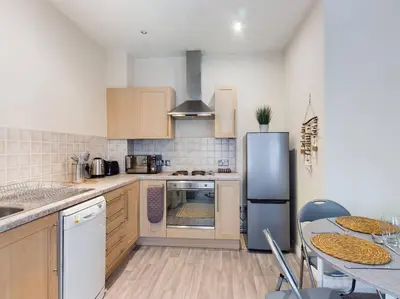 a kitchen with a refrigerator and a table with chairs at Magnificent 1BDR Apartment in Mersyside in Liverpool