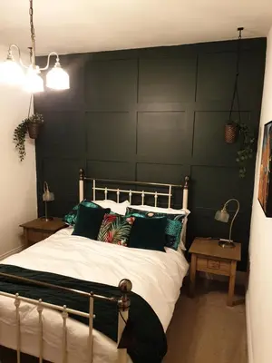 a bedroom with a large bed with green walls at Dora Cottage in Formby
