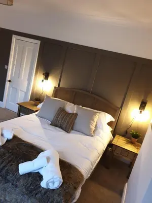a bedroom with a large bed with two white towels on it at Dora Cottage in Formby